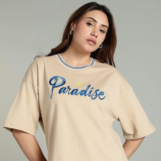 Woman wearing a beige t-shirt with 'Paradise' text on a gray background